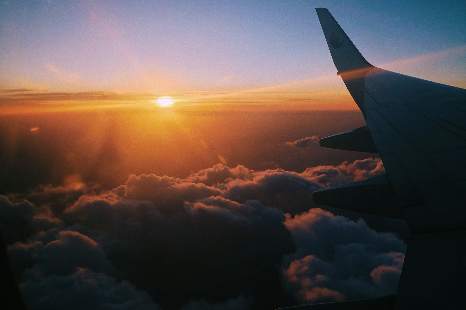 Airplane wing above the clouds at golden hour